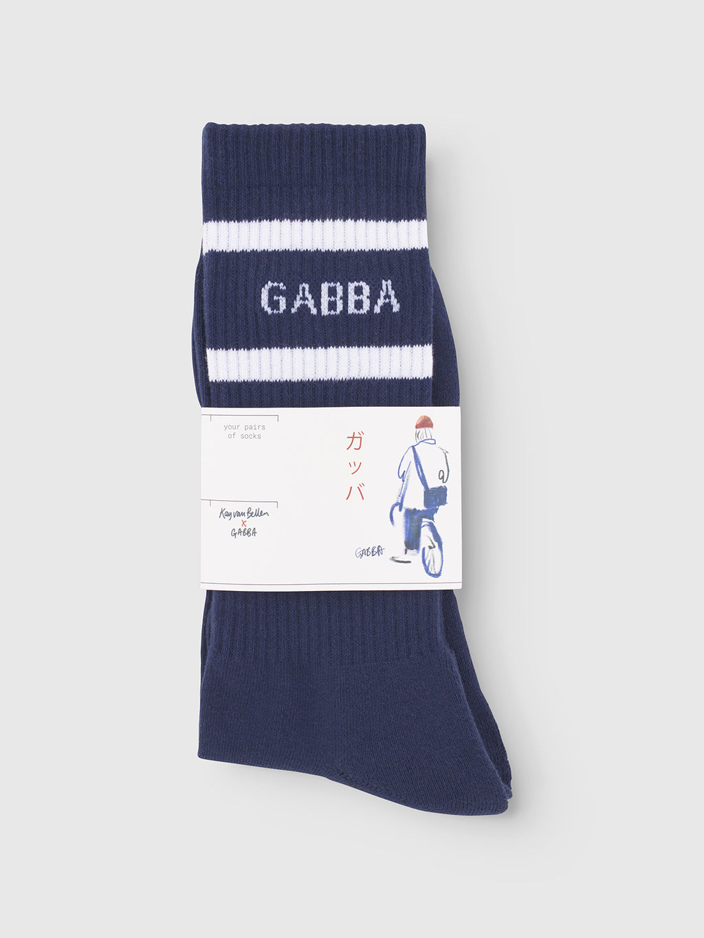 Gabba Zino Socks - Navy: cotton blend socks with two white stripes and GABBA knit in white, wrapped in a label featuring Japanese text and a cyclist illustration—perfect for everyday wear.