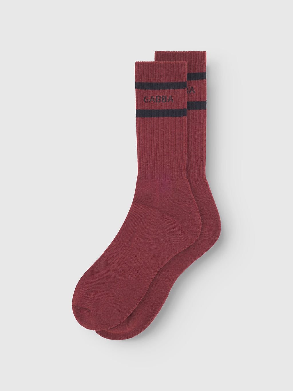 A pair of Zino Socks - Red Russet by Gabba, featuring a black stripe and GABBA above it, offers premium comfort. Shown on a light gray background, these maroon socks add style to any outfit.