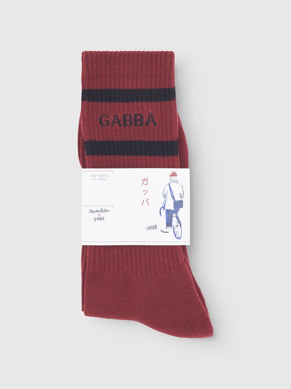 Experience premium comfort with Gabbas Zino Socks - Red Russet: folded red socks with two black stripes and GABBA on the cuff, wrapped in a white label with Japanese text and a cyclist illustration.