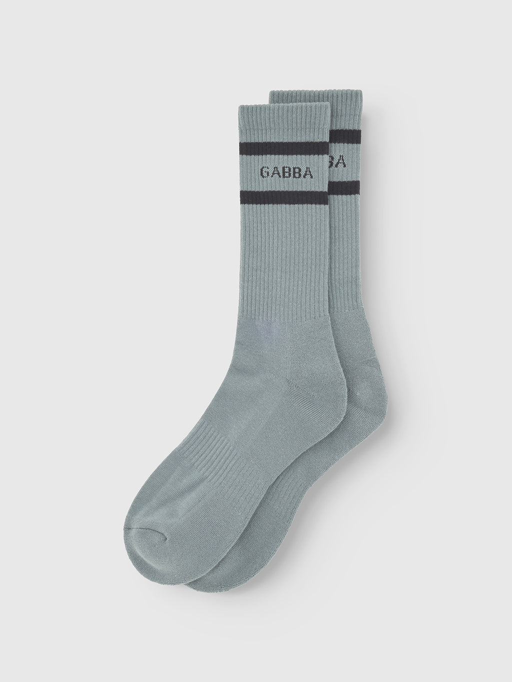 A pair of dust sage green cotton blend Zino Socks by Gabba with a ribbed texture, two dark blue stripes, and GABBA near the top are laid flat on a white background.
