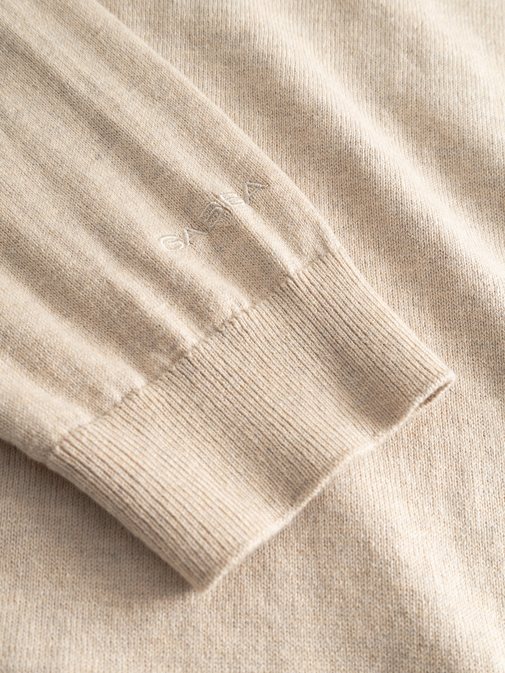 Close-up of the sleeve cuff of the Gabba Aris Prex - Sand knit sweater, highlighting its beige ribbed texture and subtle embroidered text near the cuff.