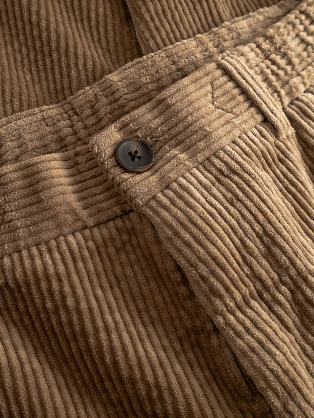 Close-up of Gabba Monza Ibre - Sand trousers, featuring tan corduroy with vertical ridges, a waistband, and black button—blending comfort stretch fabric and casual sophistication.