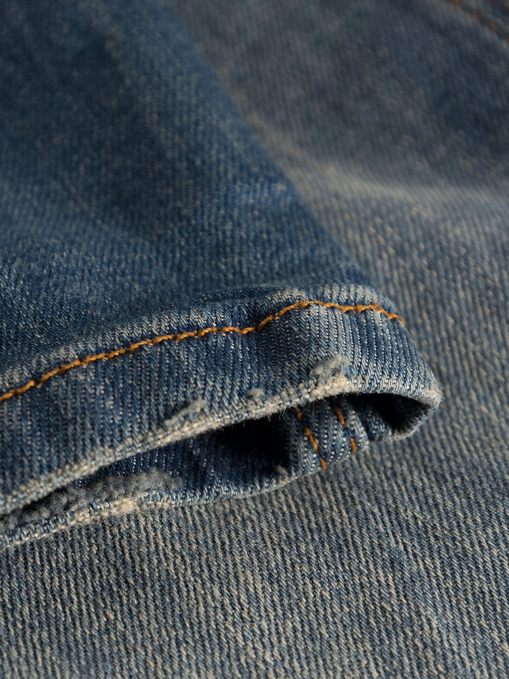 Close-up of Rey 44617 Jeans - Denim wash by GABBA, showing the blue jean cuff with iconic orange stitching. The texture and weave highlight a rugged, laid-back look.