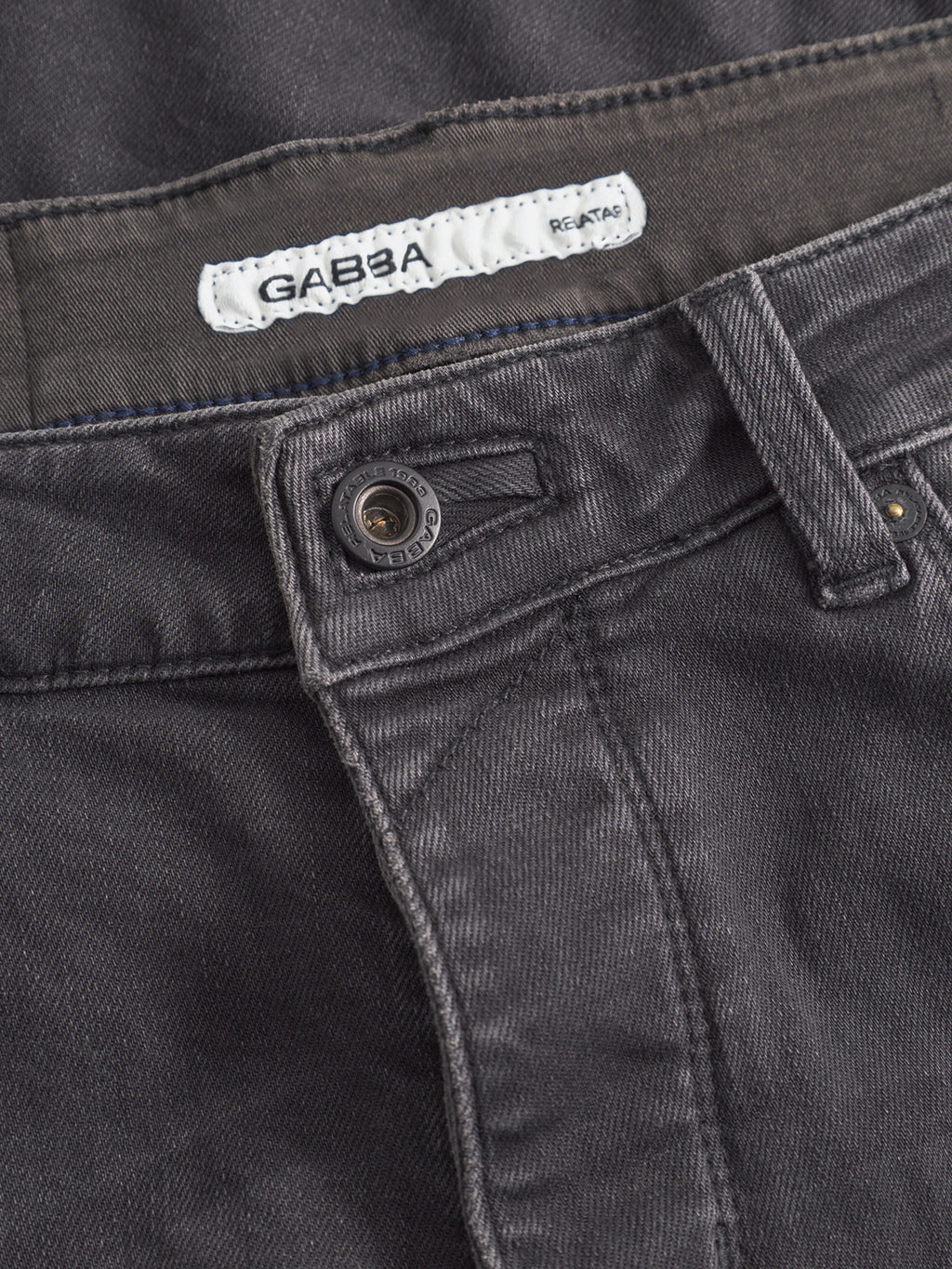 Close-up of the waistband and button of dark gray Rey Thor Jeans - Denim wash by GABBA, featuring the inner brand label. The slim fit denim’s texture and stitching details enhance its laid-back appeal.
