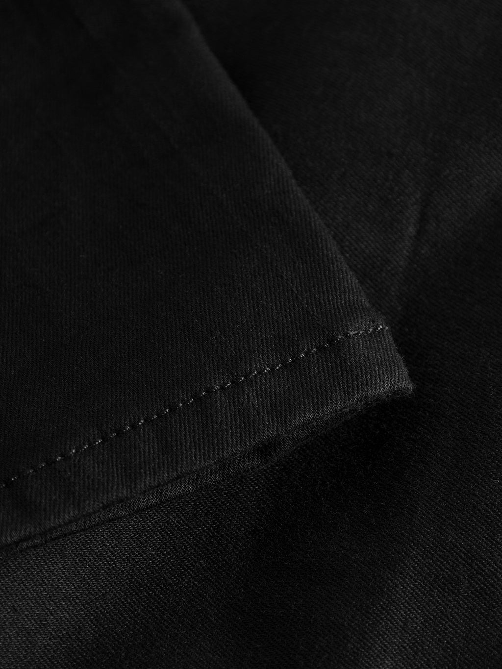 Close-up of the hem on GABBAs Jones K1911 Black Jeans shows fine stitching along the edge. The black denim is smooth, slightly textured, and crafted from super-stretch fabric with a neatly sewn seam.