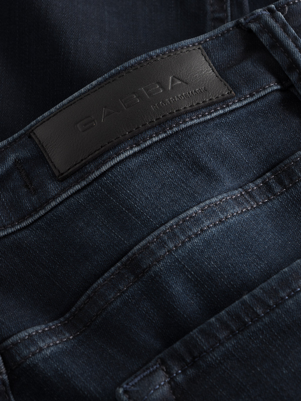 Close-up of Jones K2291 - Denim wash by GABBA, featuring visible stitching, reinforced pockets, and a black leather patch with embossed branding on the waistband. The super-stretch fabric enhances texture and color for comfort in a sleek, slim silhouette.