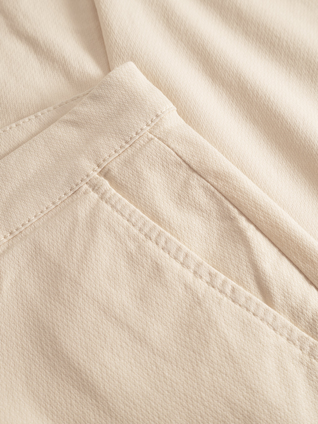 A close-up of the Gabba Paul K3280 Dale Chino in Ecru Light showcases detailed stitching on the French pocket and seam. The texture emphasizes quality, while branded buttons add sophistication. Its neutral tone epitomizes simplicity and elegance.