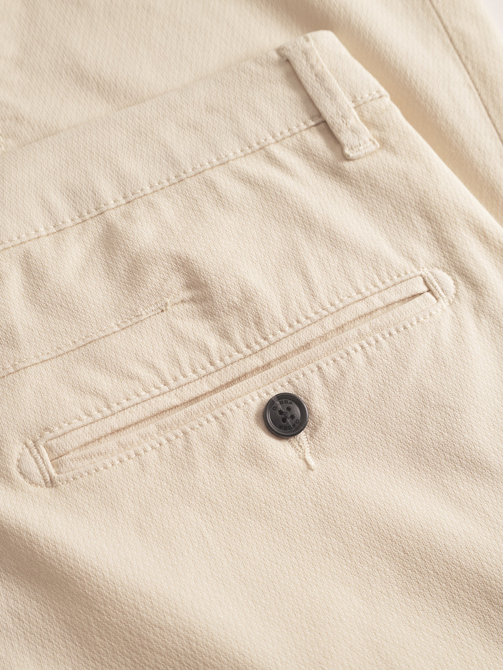 A close-up of the Gabba Paul K3280 Dale Chino - Ecru Light shows a back pocket with button closure, highlighting fabric texture and stitching details that emphasize its craftsmanship and stylish design with French pockets.