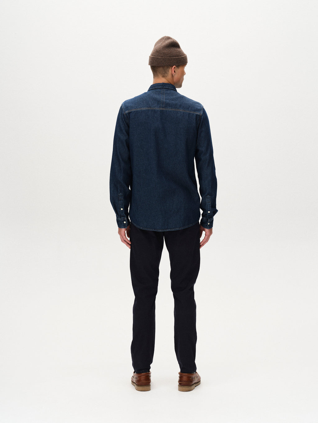 A person faces away from the camera, wearing a brown beanie, dark denim shirt, and GABBA’s Paul K3280 Dale Chino in Navy with French pockets—modernizing a classic look against a plain white background.