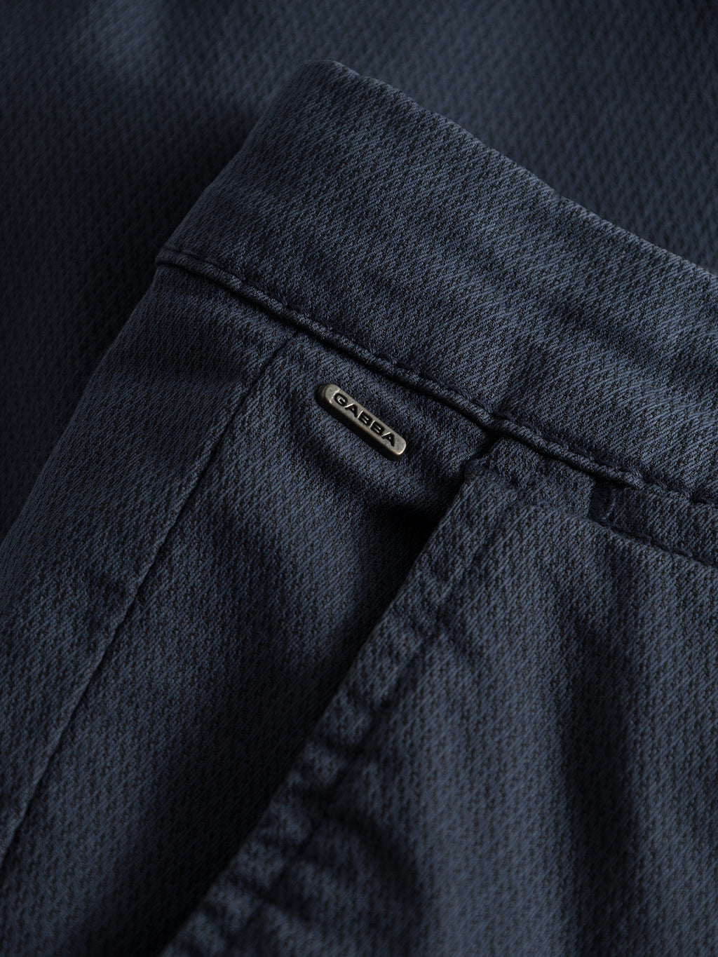 Close-up of dark navy Paul K3280 Dale Chino pants by GABBA, featuring French pockets and detailed stitching with a small metal tag with the brand name above the back pocket.