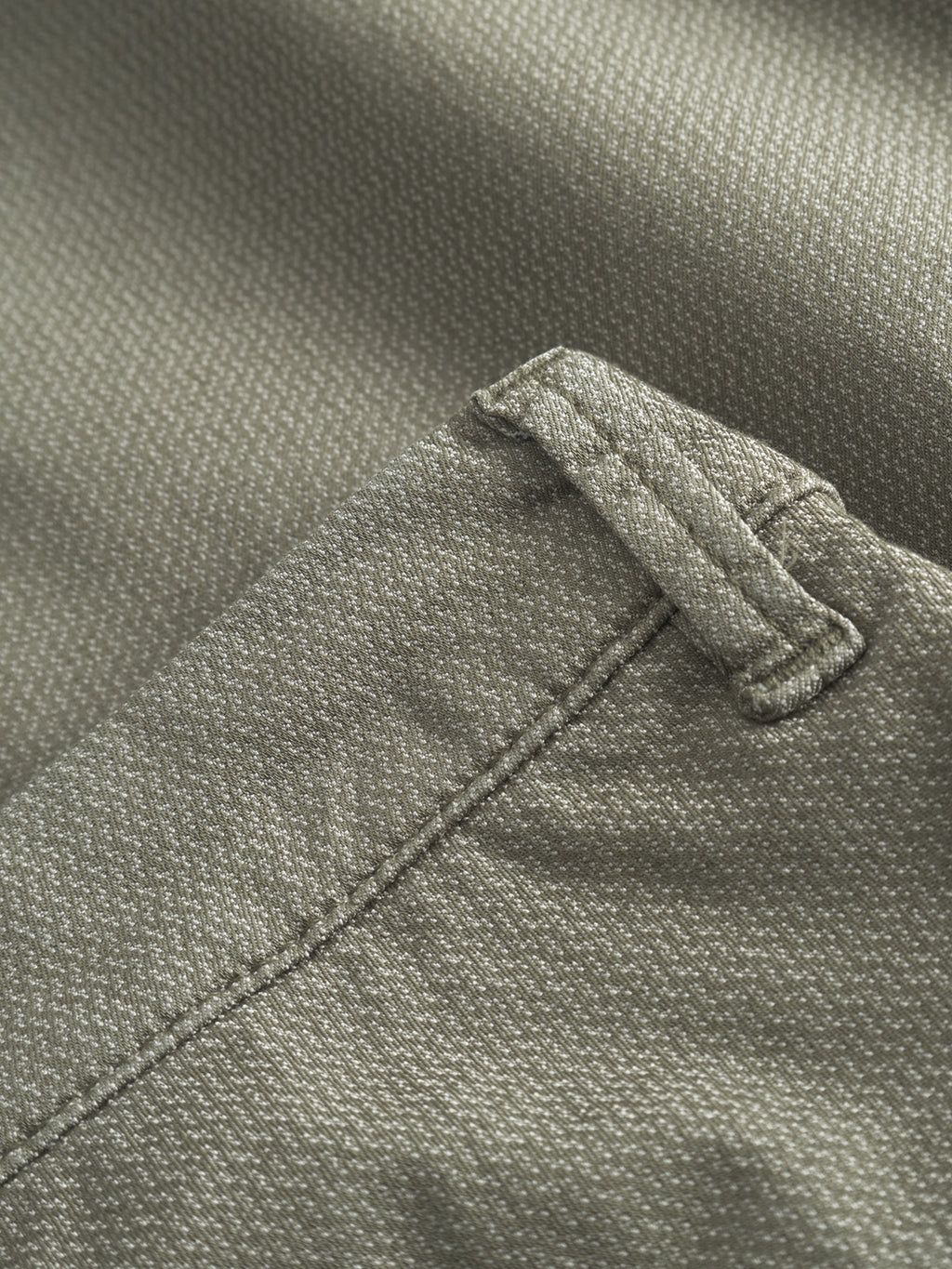 A close-up of olive green fabric on the Paul K3280 Dale Chino by Gabba showcases a textured pattern with detailed stitching and a small loop, likely part of French pockets or utility design, highlighting Gabbas craftsmanship.