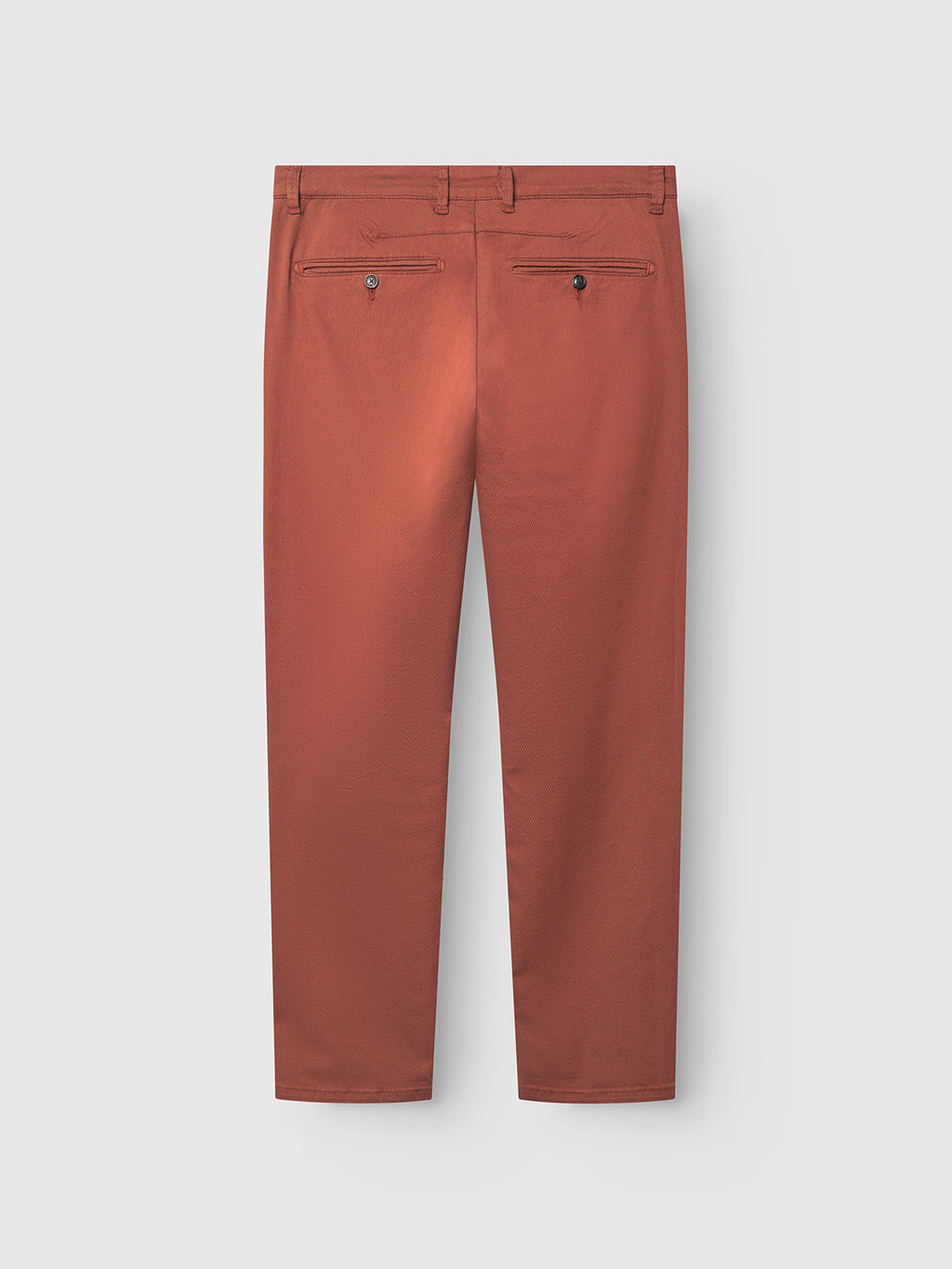 The Gabba Paul K3280 Dale Chino in Brown Rust is shown from the back on a light gray background, featuring a slim, straight-leg cut with French pockets, two buttoned welt pockets, and belt loops.