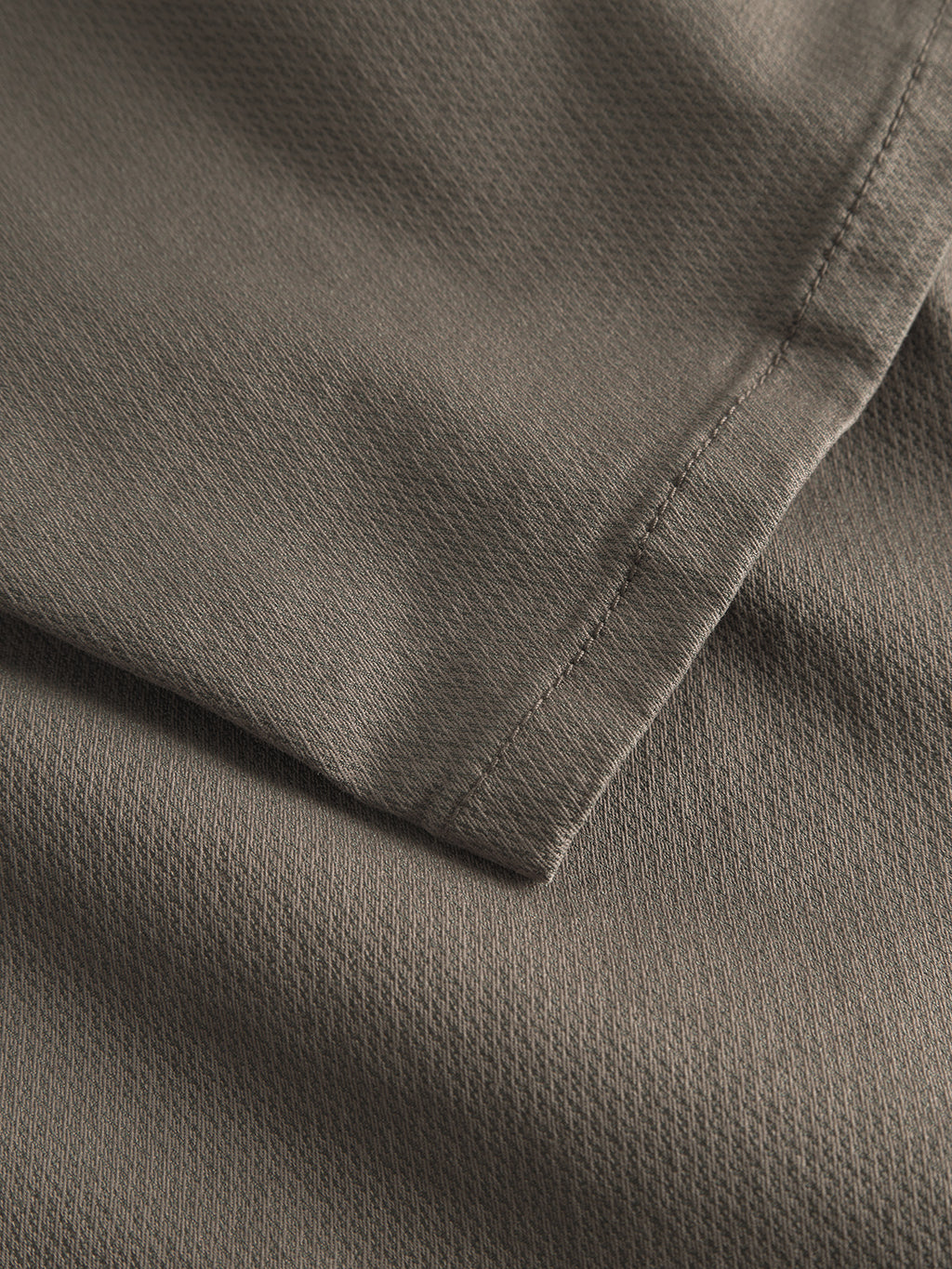 Close-up of a folded piece of dark brown textured fabric used in Paul K3280 Dale Chino by Gabba. Visible stitching along the edges highlights its weave and soft appearance, reminiscent of classic gabba craftsmanship.