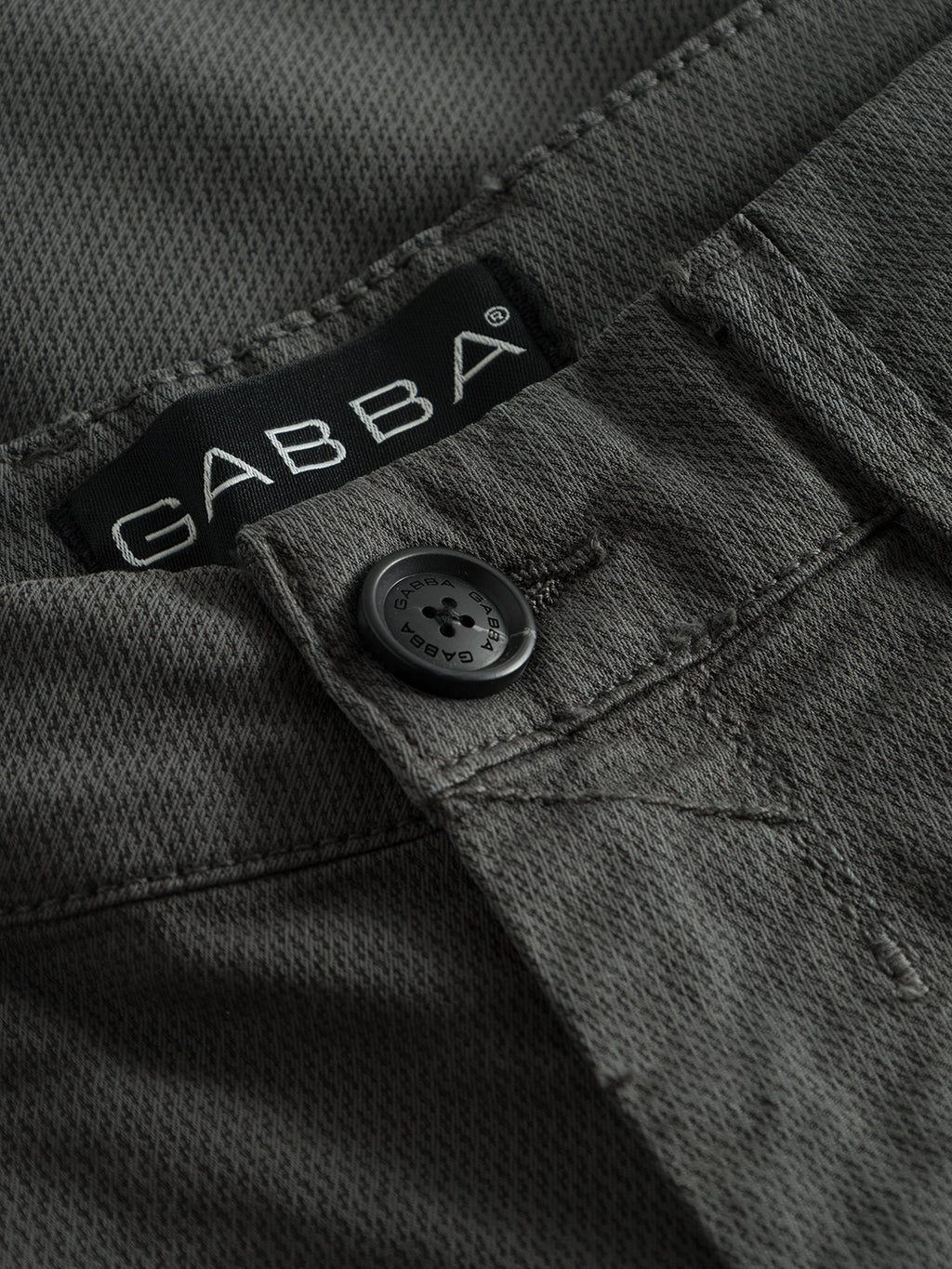 Close-up of the gray-textured Paul K3280 Dale Chino featuring a black GABBA-branded button and a brand label near the waistband, with stylish French pockets for elegance.