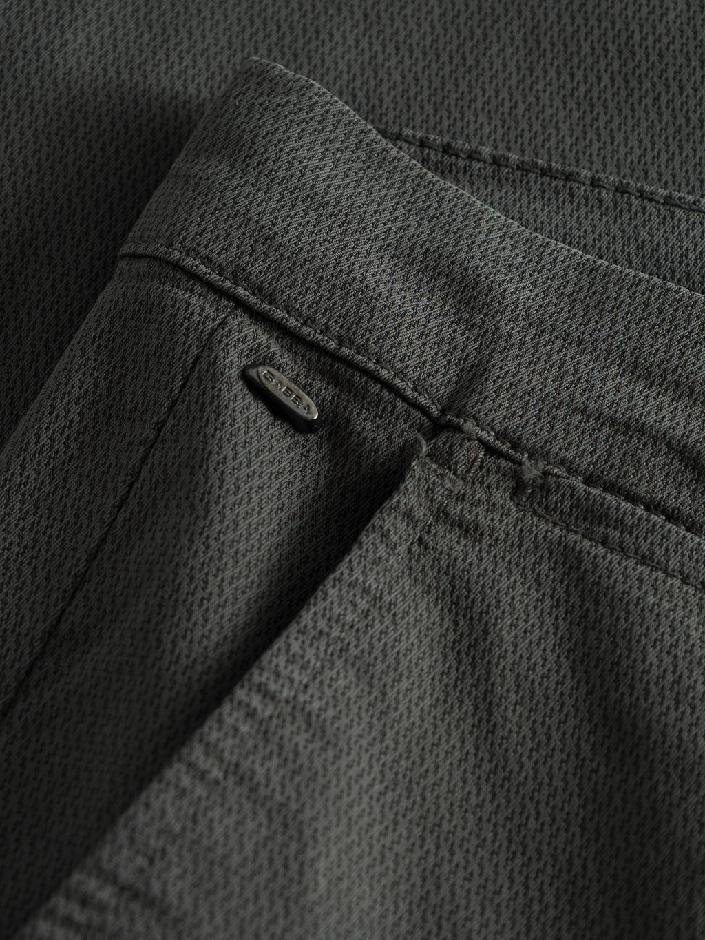 Close-up of GABBAs Paul K3280 Dale Chino - Grey, featuring elegant French pockets, a back pocket with a small metallic brand tag by the seam, and a subtle grid pattern on dark gray textured fabric.