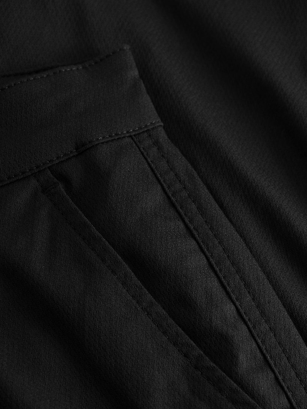 Close-up of the smooth, slightly matte black super stretchy fabric with visible stitching and a seam from the GABBA Pisa Cargo K3280 Dale Pants, showing part of a cargo side pocket.