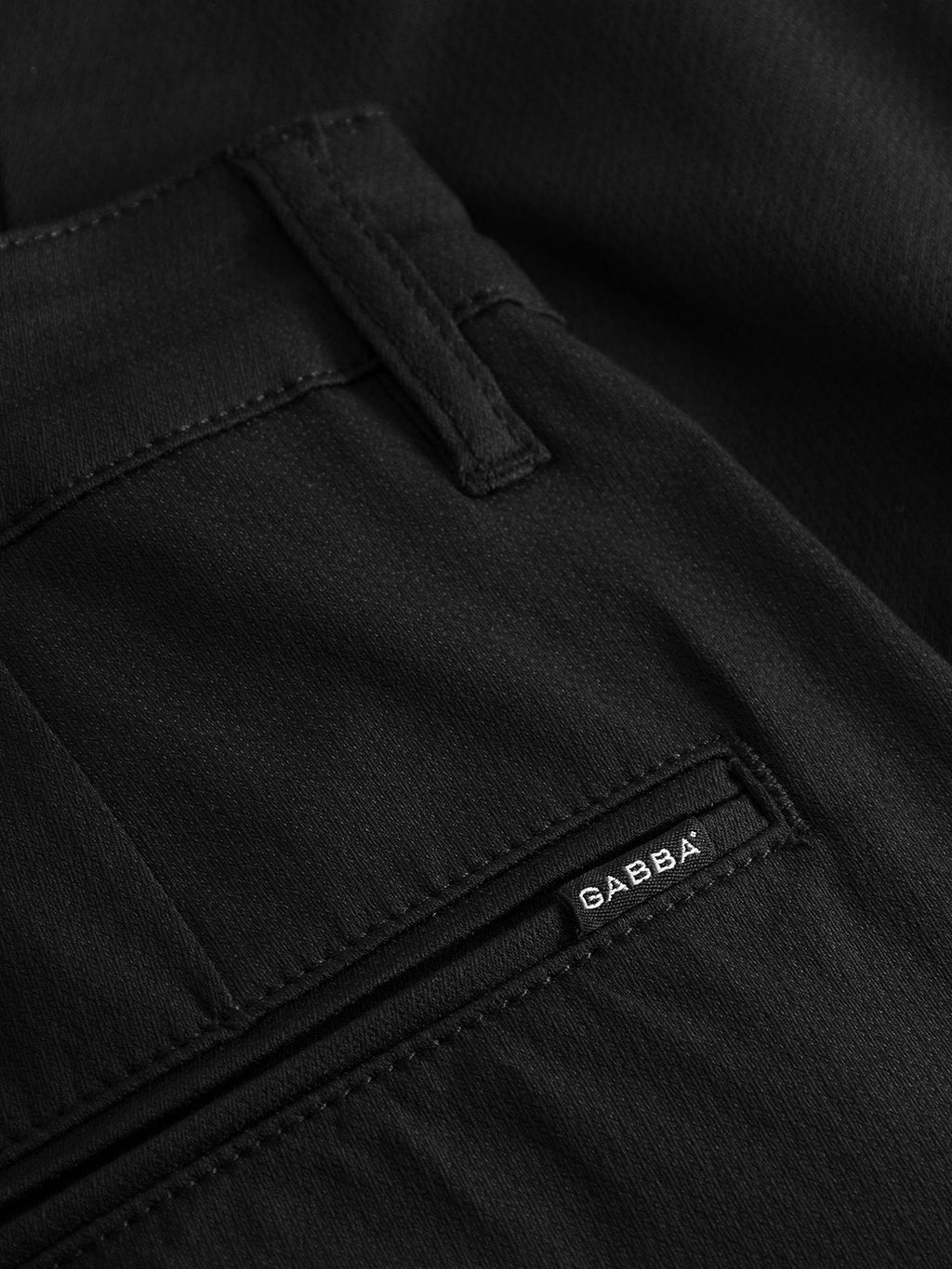 Close-up of GABBA Pisa Cargo K3280 Dale Pants in black, showing a back pocket with zipper and branded label. Made from super stretchy fabric with detailed stitching and a slim tapered fit for comfort and style.