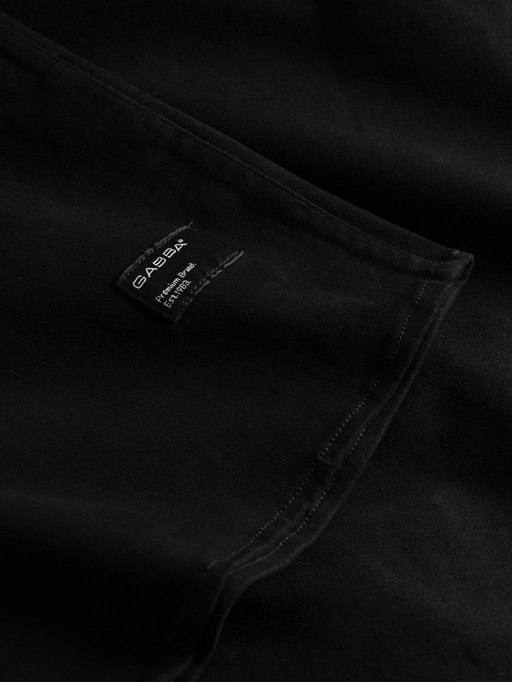 Close-up of GABBAs Topper LS Shirt in black, ideal as a versatile overshirt. It includes a small label with brand and size details, while the texture of the high-quality fabric stands out.