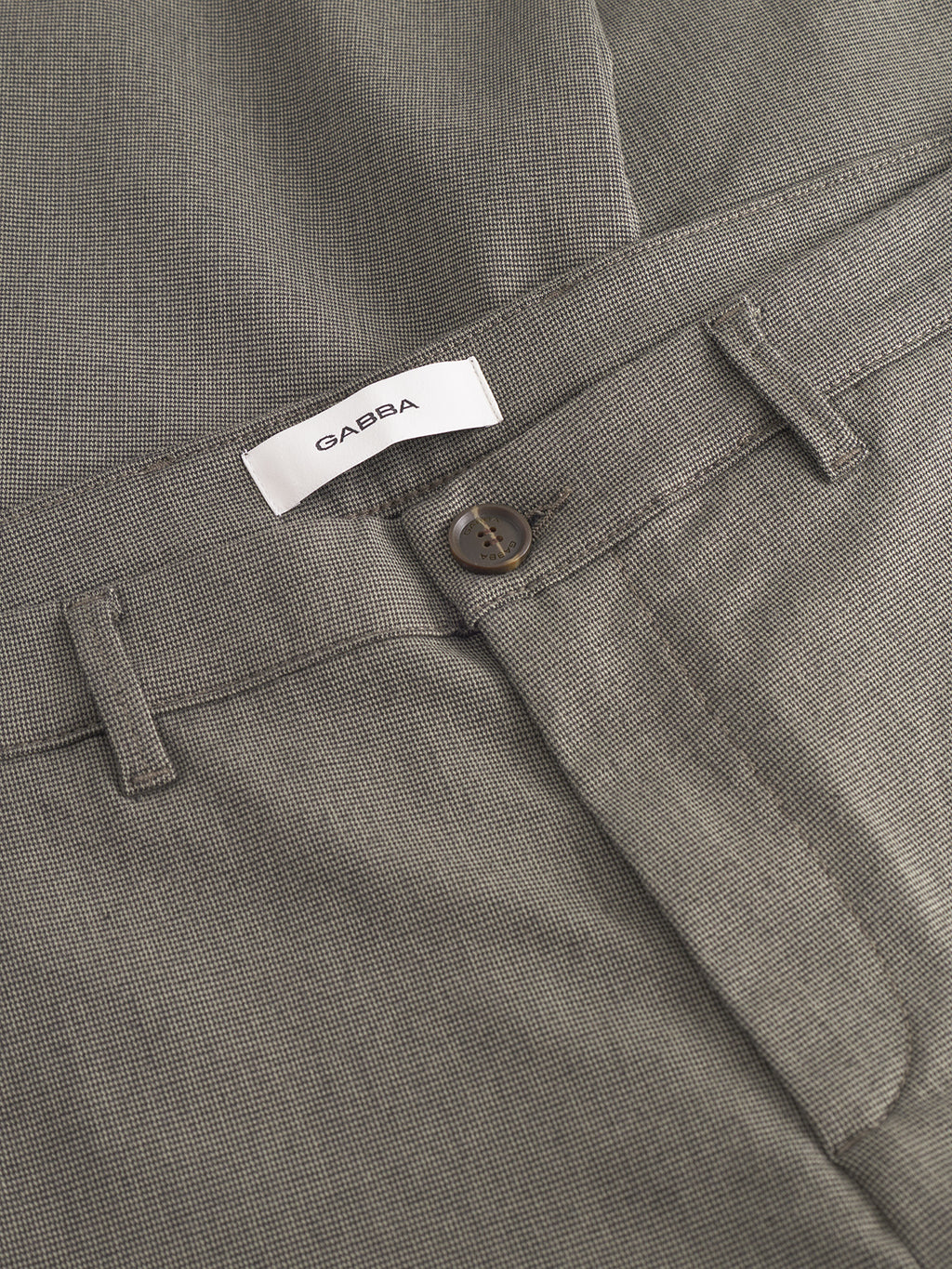 Close-up of the waistband and button of Pisa Domo Pants - SS25Army in light brown with belt loops, made from high-stretch fabric, featuring a white Gabba label.