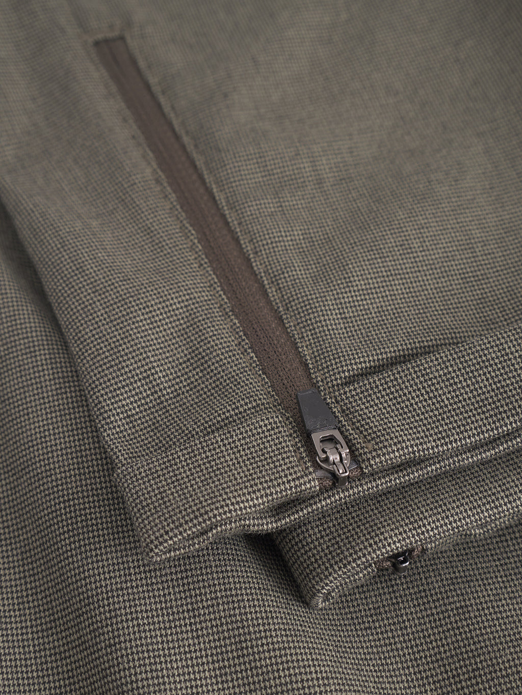 Close-up of the textured, olive-green high-stretch fabric on the Gabba Pisa Domo Pants - SS25Army, showing a fine grid pattern and a partially unzipped pocket with branded Gabba Pisa zippers.