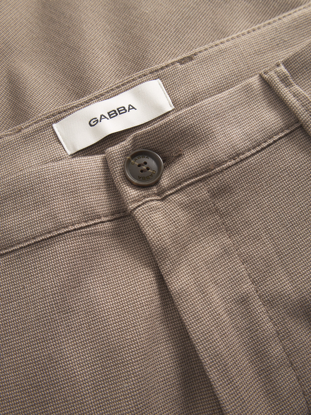 Close-up of Gabba Pisa Domo Pants in khaki, made from high-stretch cotton-blend fabric with a black button, signature Pisa zippers, and a white GABBA label inside the waistband for a refined metro look.