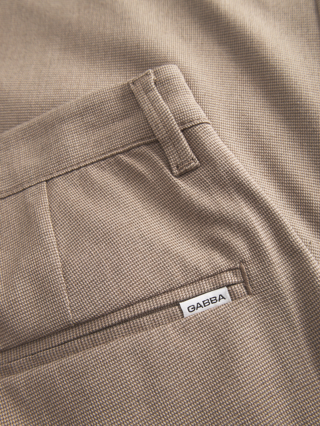 Close-up of Pisa Domo Pants - Khaki by Gabba, featuring smooth, finely woven high-stretch cotton-blend fabric and a back pocket detailed with a small white Gabba label.