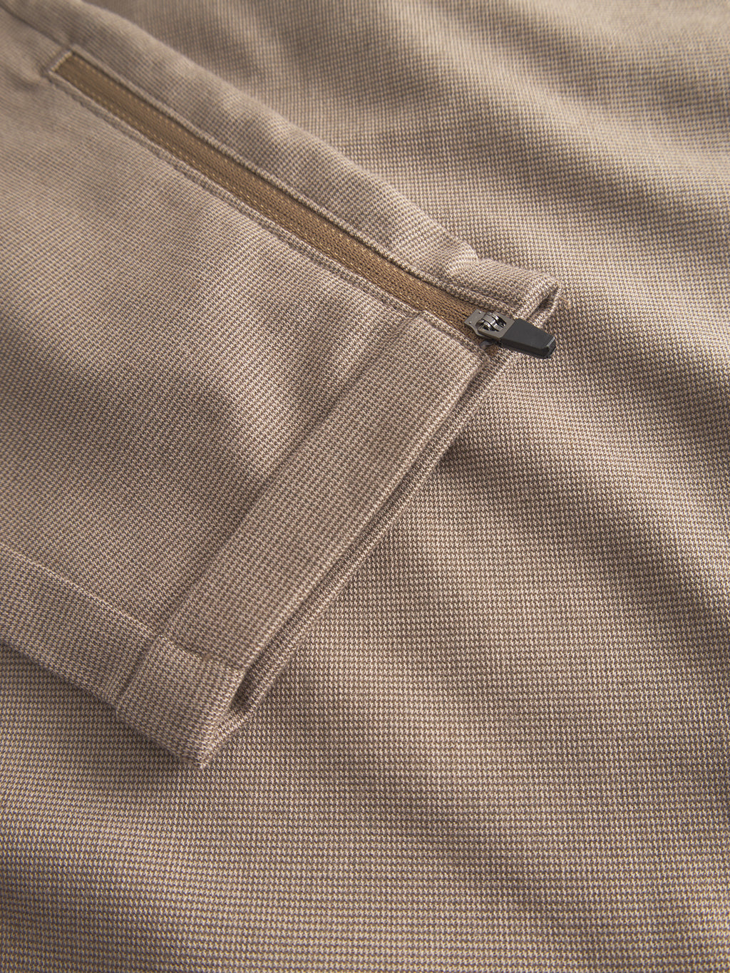 Close-up of Gabba Pisa Domo Pants in khaki: high-stretch cotton-blend fabric with a textured pattern and a metallic zipper pocket—perfect for adding subtle metro style.
