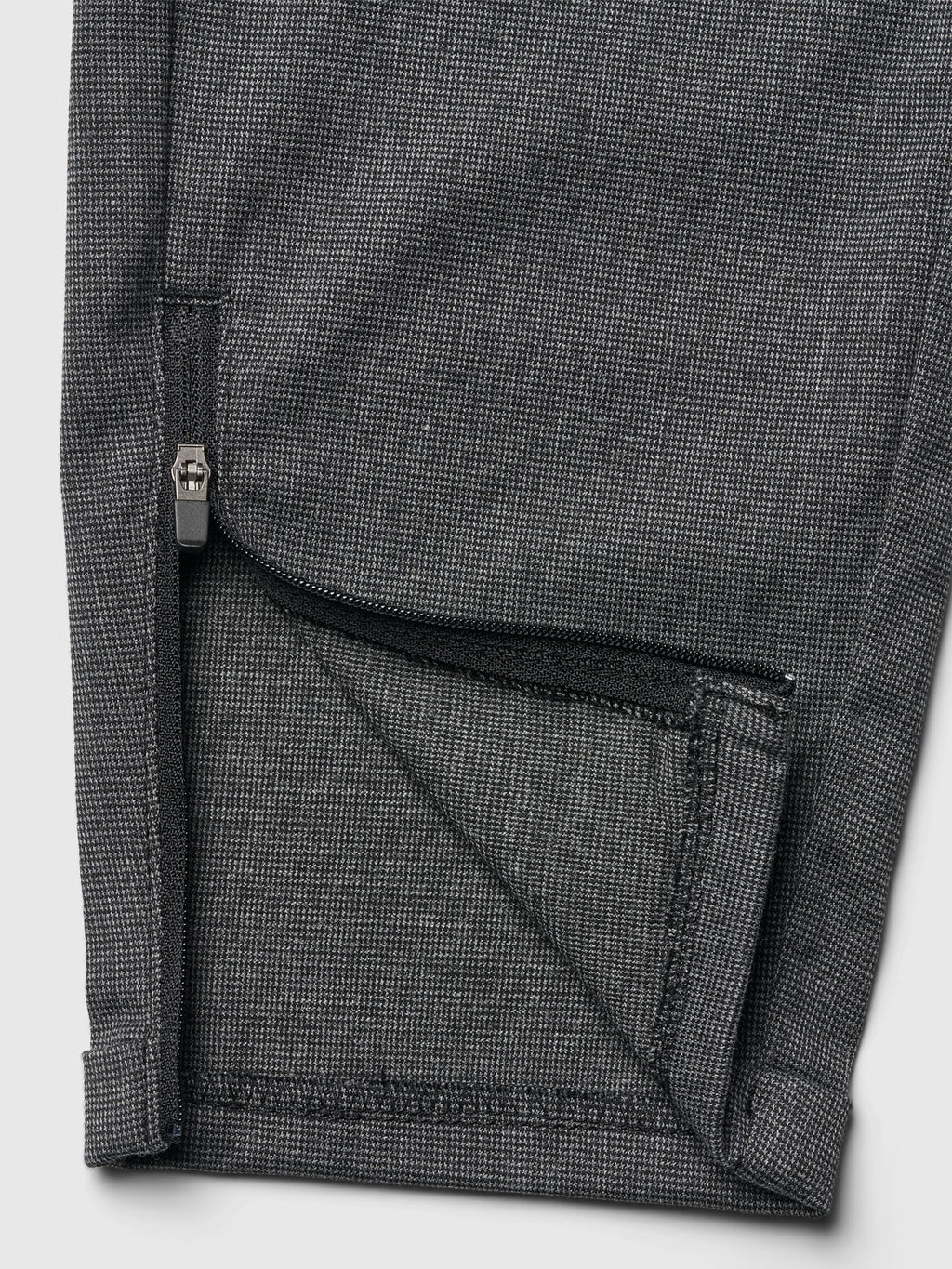 Close-up of the hem on Gabba Pisa Domo Pants in dark grey, featuring a partially unzipped cuff that reveals inside fabric and stitching—highlighting signature metro style details.
