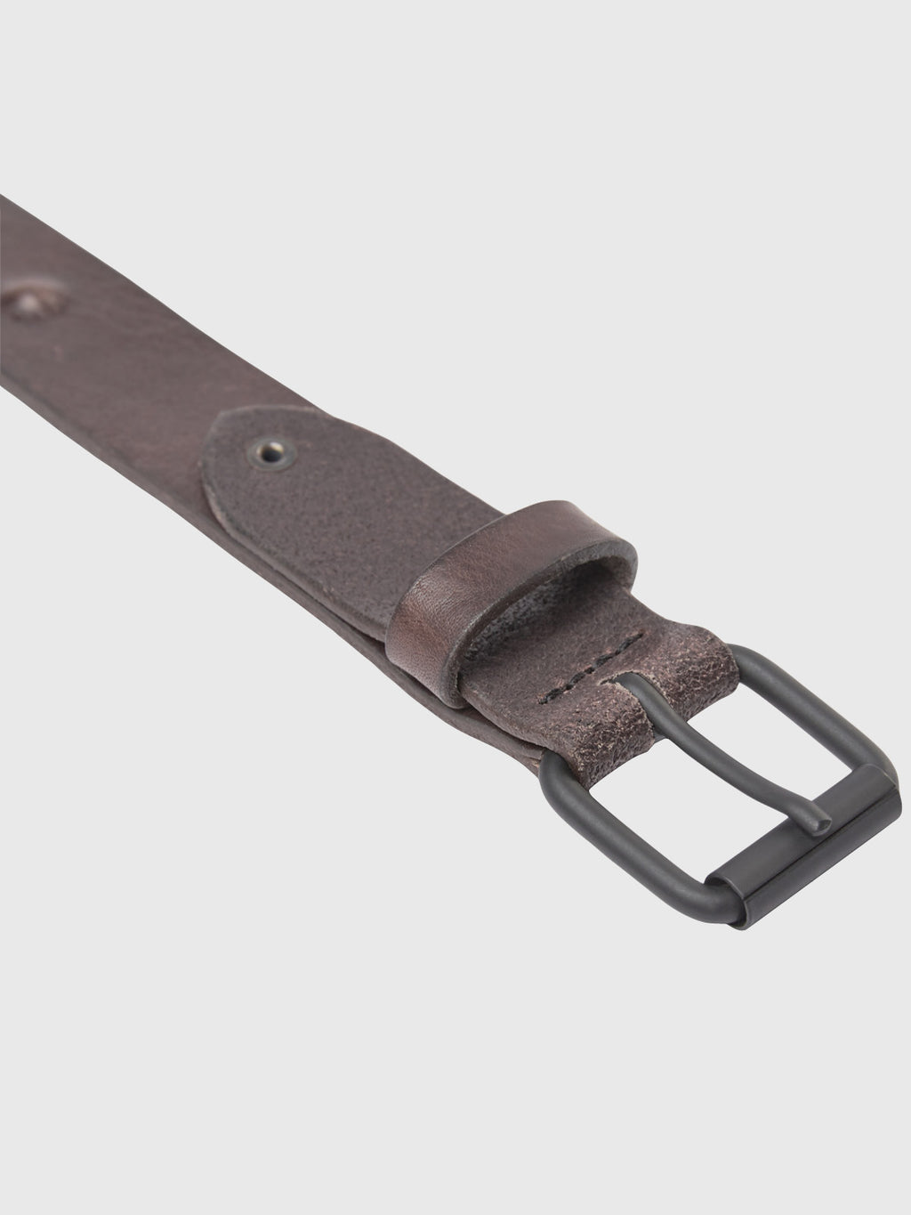 Close-up of the GABBA Okay Point Belt in brown leather, featuring a black metal buckle. It has size-adjustable holes and a stitched edge design, shining against a light grey background—a classic piece for timeless style.