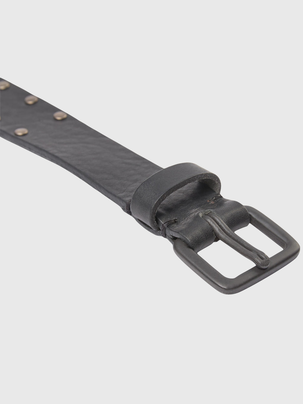 A close-up of the Okay Stud Belt - Black by GABBA, featuring a raw leather finish, square metal buckle, and eye-catching studs on one side set against a light gray background.