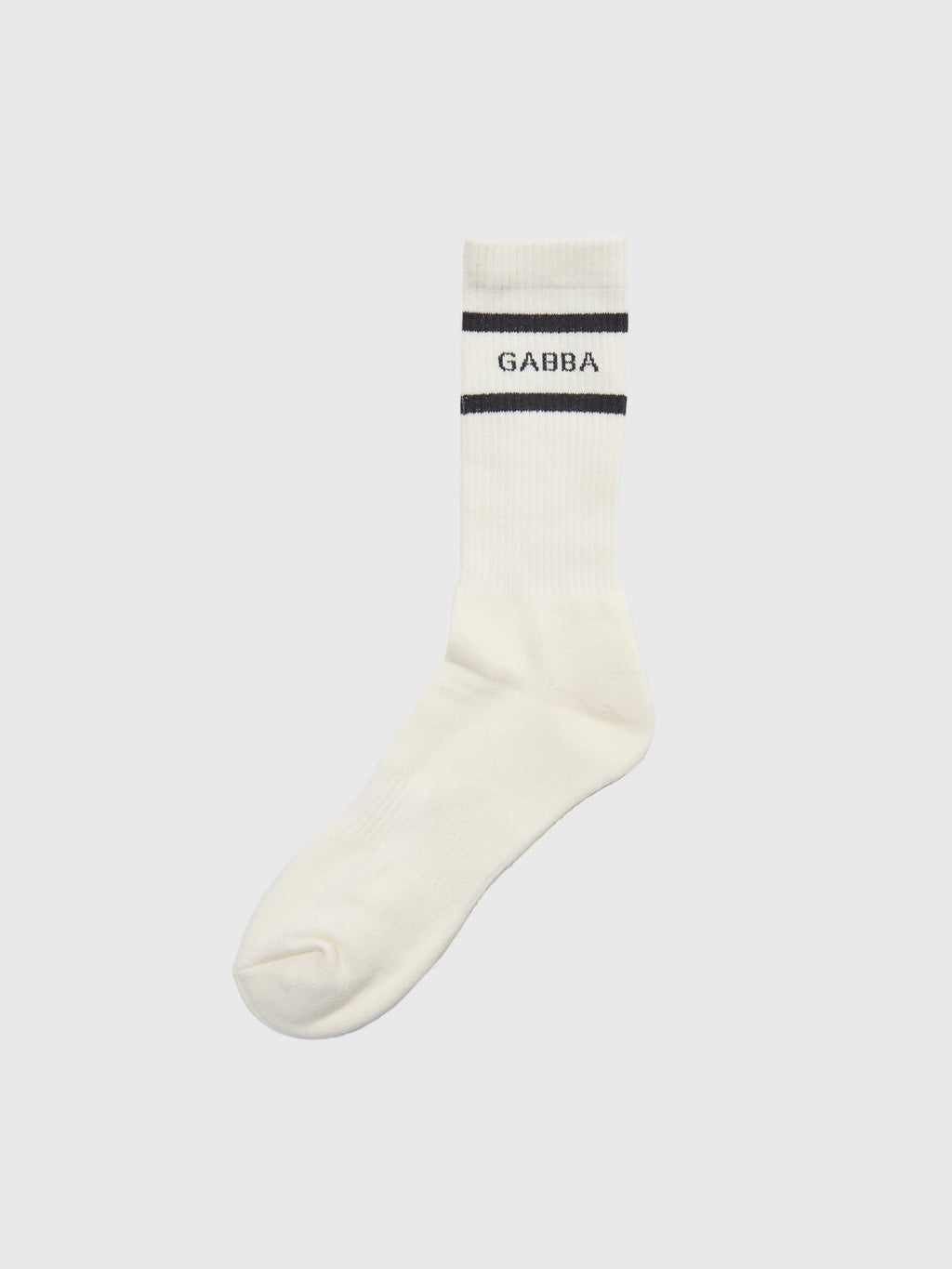 The Loris Socks - White by GABBA feature a single white sock with two black stripes and GABBA interwoven between them. Its ribbed texture ensures comfort, all set against a plain, light background.
