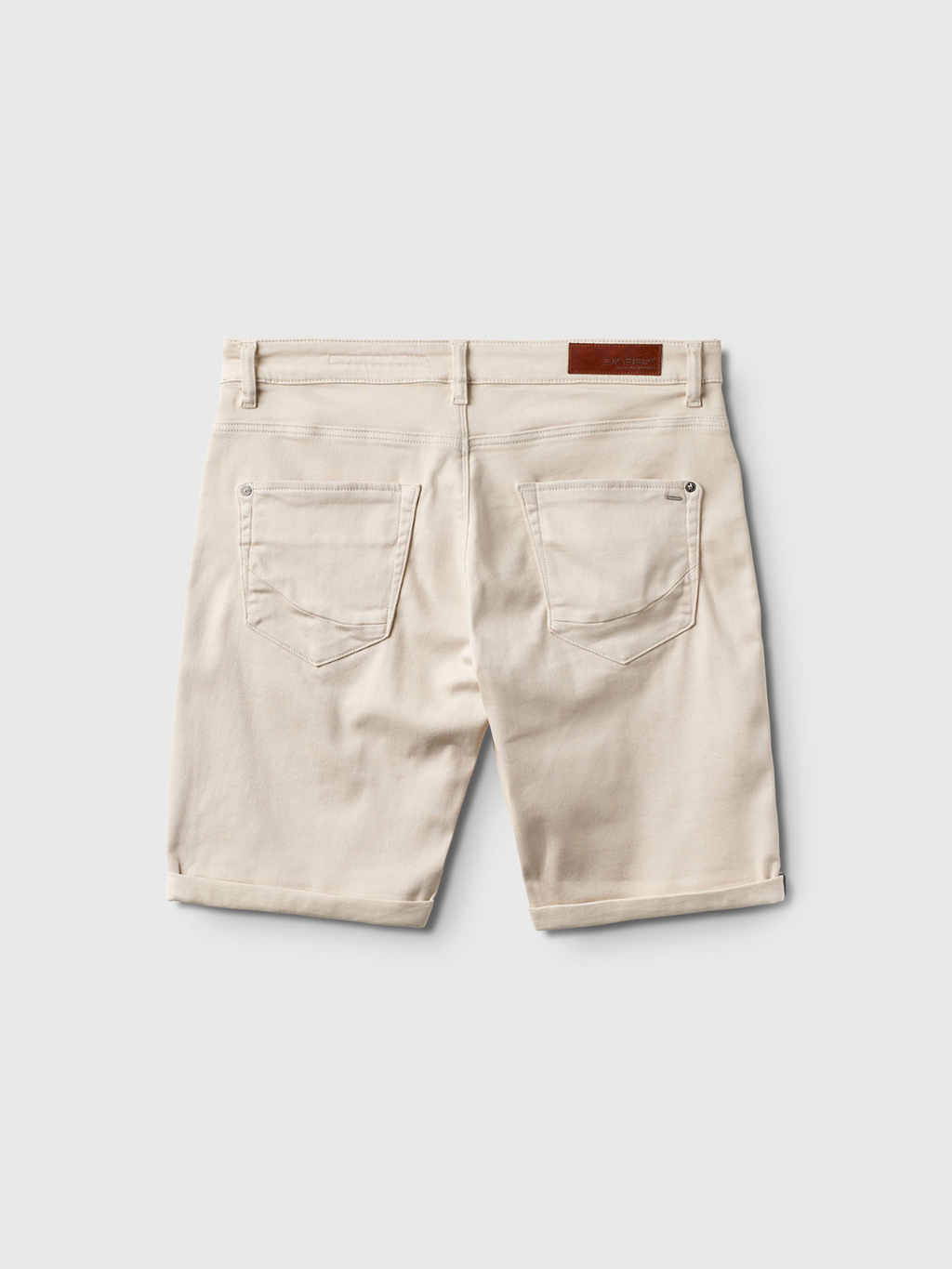 Back view of Gabba Jason K3995 SANZA Shorts in Birch—beige, knee-length denim with two back pockets, belt loops, a brown leather patch on the waistband, and super stretch fabric, shown against a light gray background.