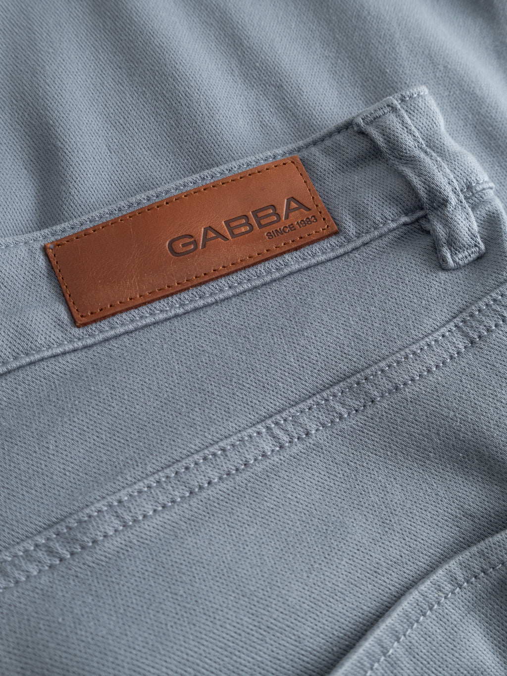 Close-up of Gabba GABjason K3995 SANZA Shorts in denim blue, made from super stretch fabric with visible stitching and a brown leather patch labeled 