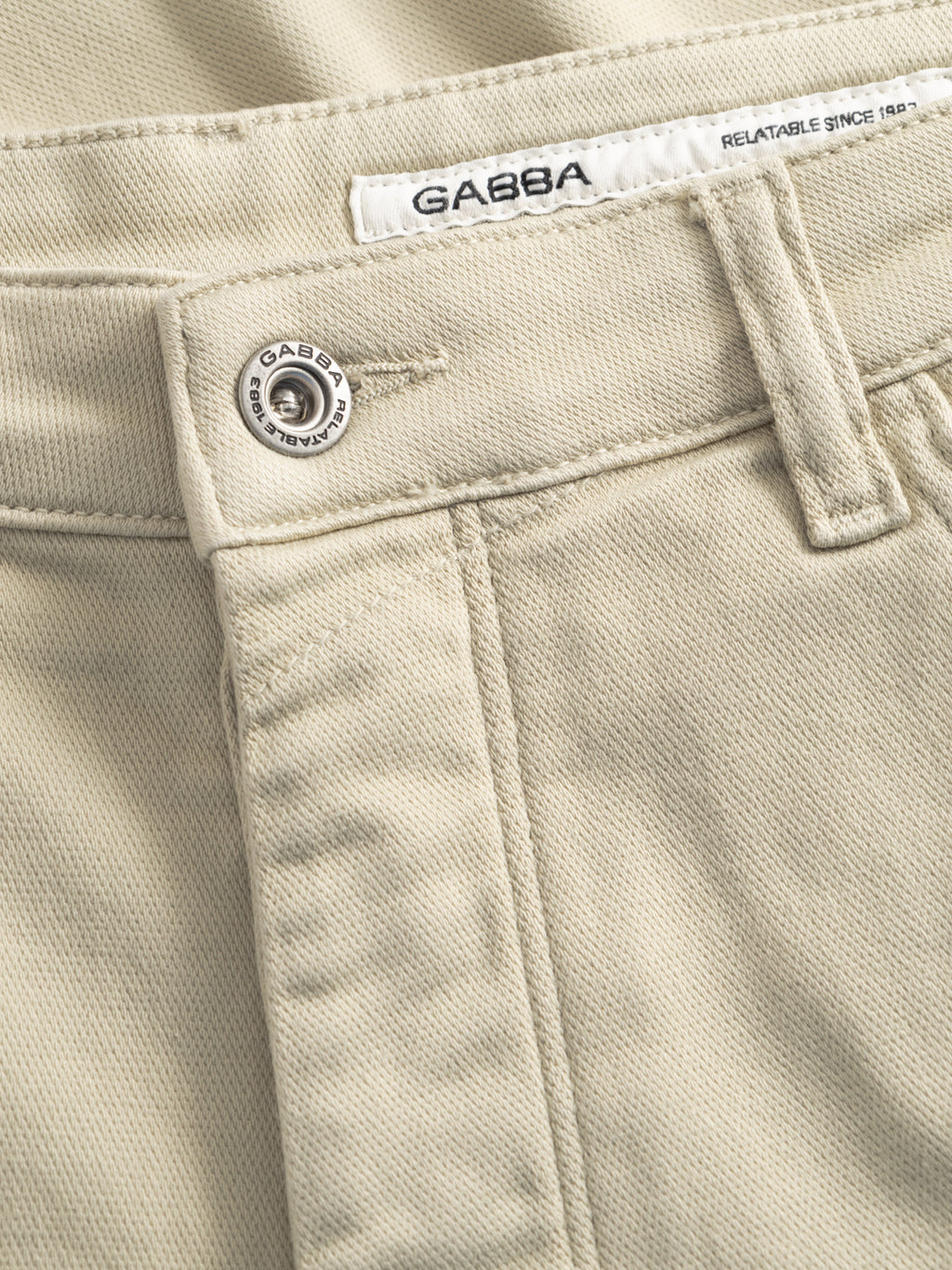 Close-up of GABjason K3995 SANZA Shorts in Alfa Green by Gabba, featuring a waistband, branded metal button, belt loops, and a white label reading GABBA and RELATABLE SINCE 1983. The knee-length design ensures comfort and versatility.