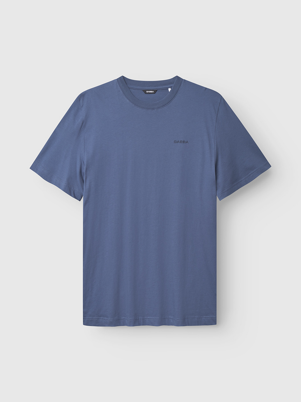 The Gabba Dune Logo SS GOTS in Vintage Indigo is a classic-fit, crew-neck t-shirt made from soft organic cotton. GOTS certified, it features a subtle logo on the left chest against a light gray background.