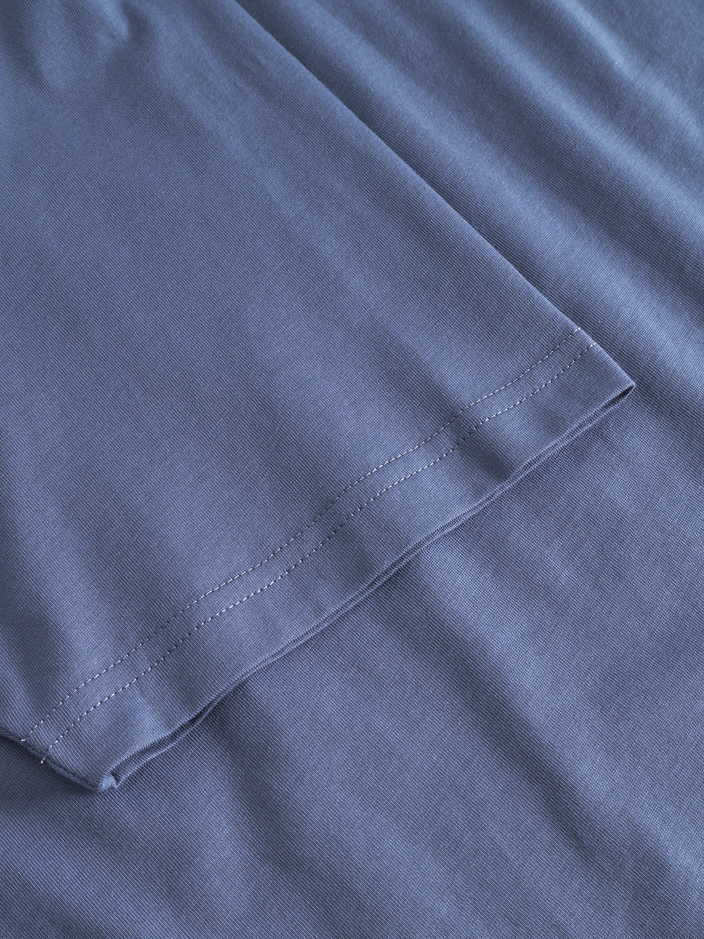 Close-up of the hem and stitching on the Gabba Dune Logo SS GOTS t-shirt in Vintage Indigo, highlighting neatly sewn seams and smooth organic cotton fabric texture.