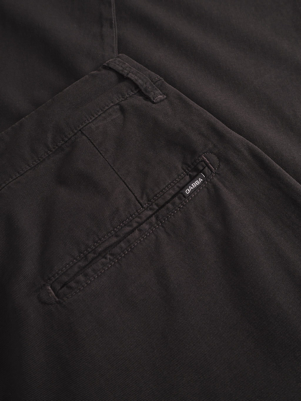 Close-up of the back pocket on Gabba’s Firenze Lubo - Black chinos, featuring a small black brand tag by the seam. These pants offer a relaxed tapered fit for modern comfort and style.