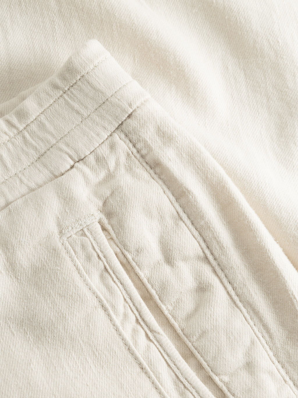Close-up of Gabbas Monza Twill Linen pant in Birch, a cream-colored relaxed straight style with visible seam and pocket stitching, textured fabric, and an elastic waist for comfort.
