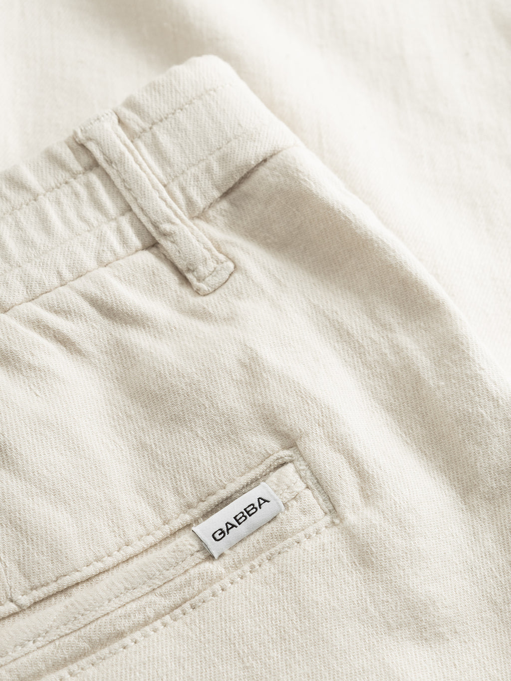 Close-up of the back pocket of Gabbas Monza Twill Linen - Birch relaxed straight pant, featuring a fabric label above the pocket. The soft, textured cotton-linen blend and elastic waist provide comfort and style.