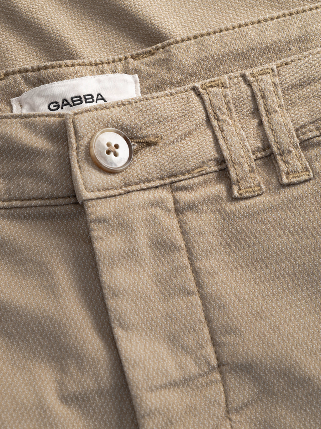 Close-up of Gabba GABjet K3280 Dale Shorts in sand, showing beige textured fabric, white button, belt loops, stitching details, front pocket, and a visible Gabba label.