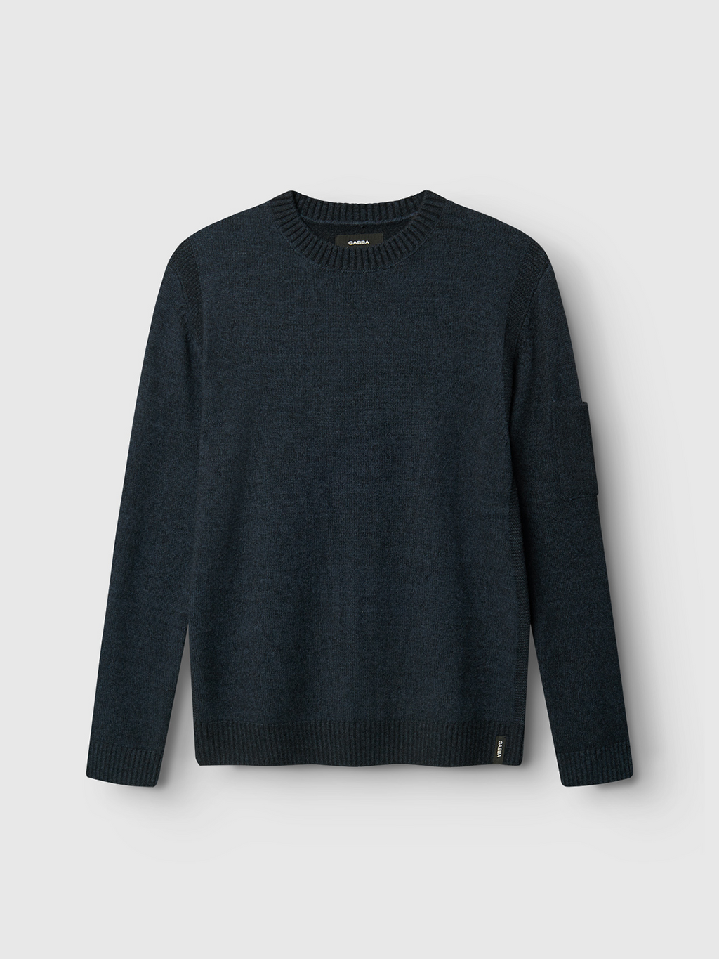 The Gabba Luca Ls - Navy is a dark navy blue wool knit sweater with a textured finish, long sleeves, crew neck, ribbed cuffs and hem, and a small patch pocket on the upper left sleeve, shown against a light gray background.