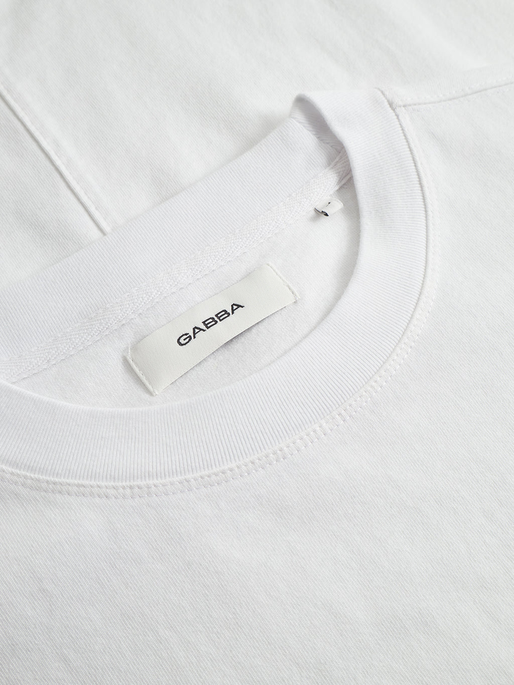 Close-up of the Nigel Wix Boxy Hour SS crew-neck t-shirt in white by Gabba, featuring a visible Gabba label inside the neckline and highlighting its modern, boxy fit.