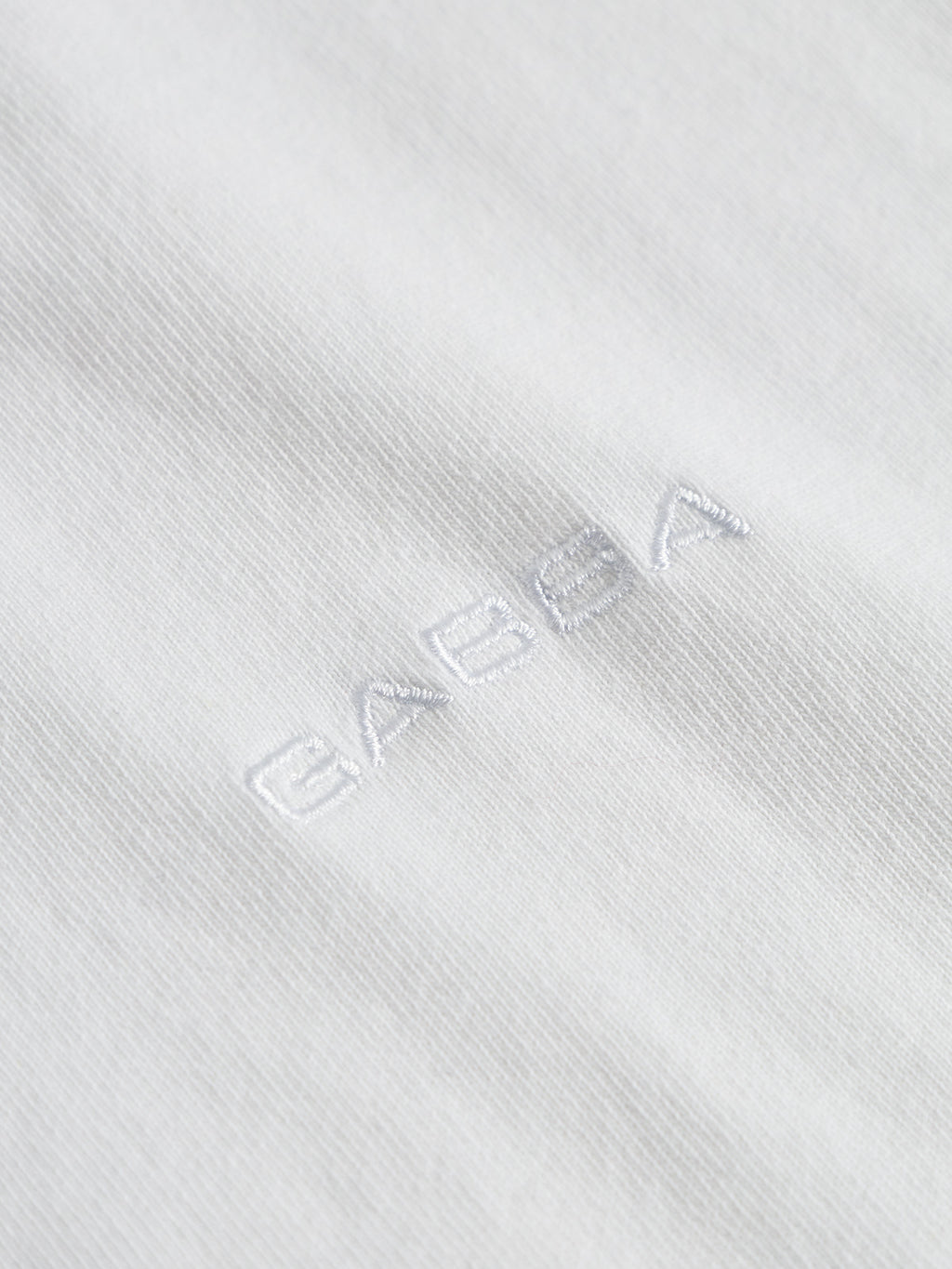 Close-up of Gabbas Nigel Wix Boxy Hour SS - White t-shirt, featuring subtle white BASGA embroidery at the center—a textured detail on this modern fit casual tee.