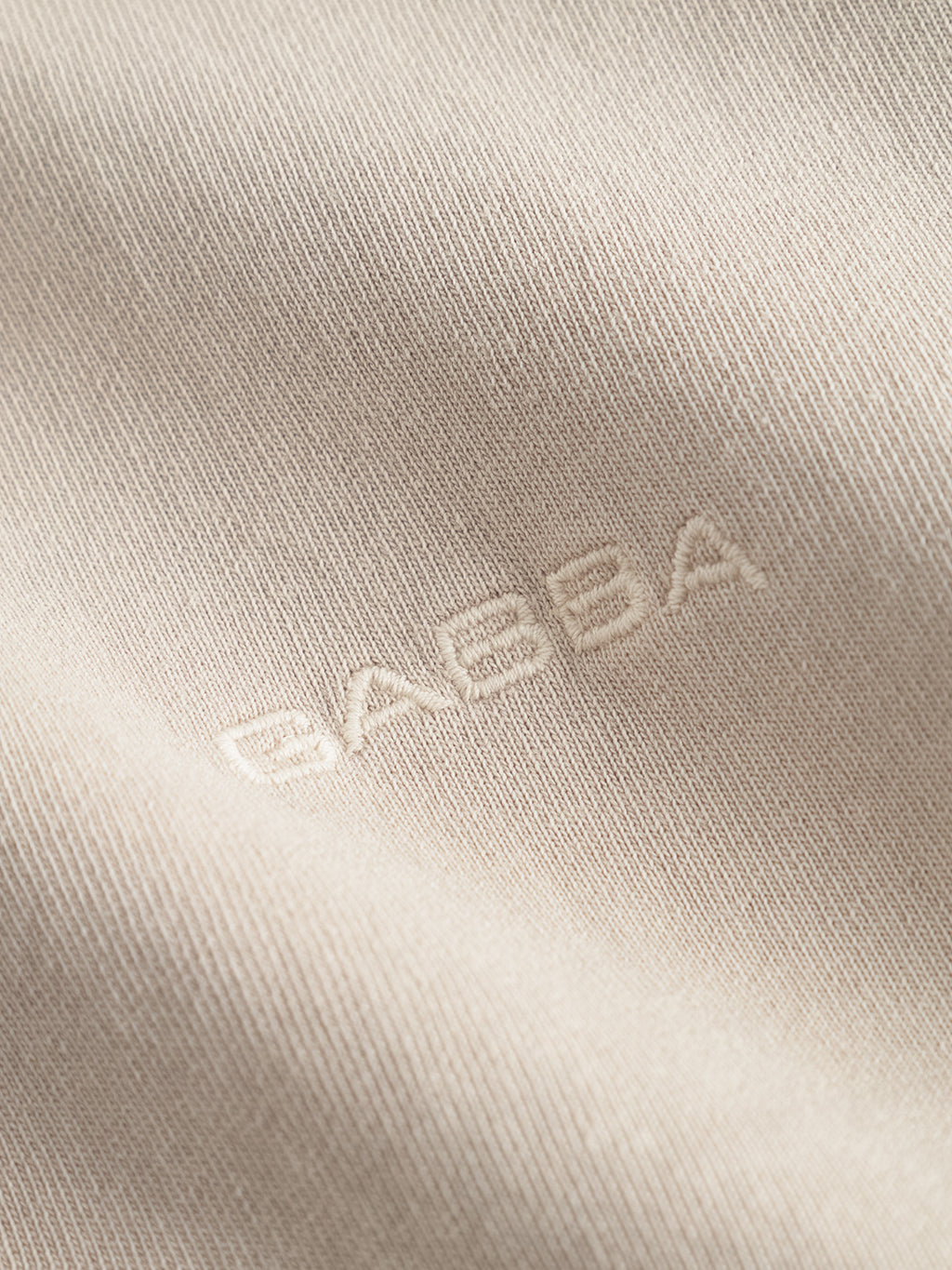 Close-up of the Nigel Wix Boxy Hour SS in Sand Cashmere by Gabba, featuring subtle GABBA embroidery in matching thread for a textured, minimal look.