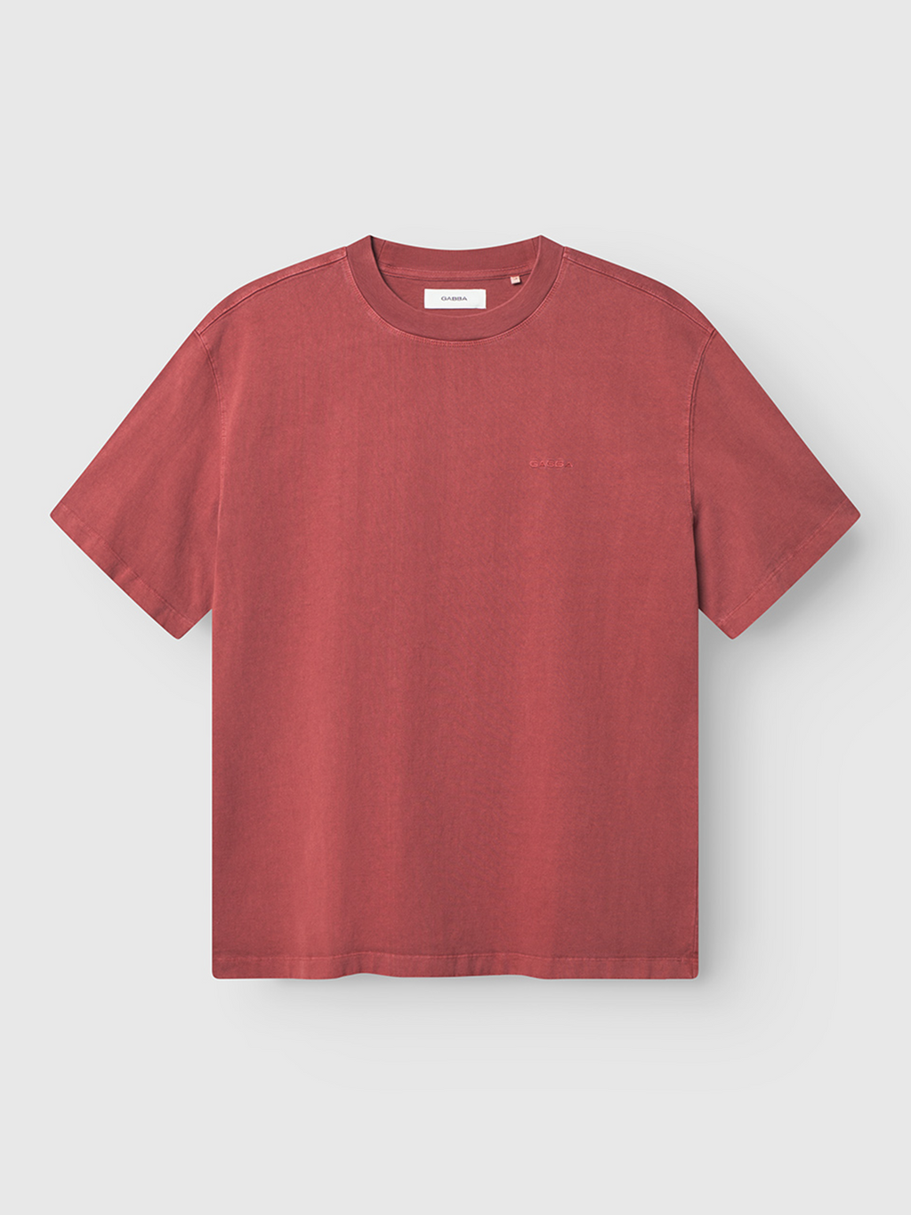 The Gabba Nigel Wix Boxy Hour SS in Red Russet is a plain, boxy-fit tee with short sleeves and a crew neckline, shown on a light gray background. Subtle seam stitching adds to its relaxed, effortless style.