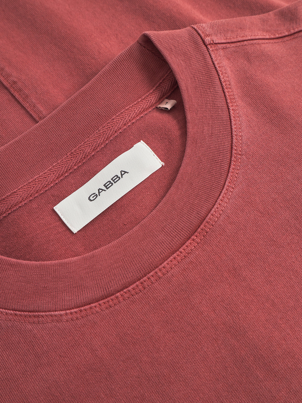 Close-up of the Nigel Wix Boxy Hour SS tee in Red Russet, showing its boxy fit, visible heavy-weight cotton texture, and an inner collar label with the Gabba brand name.