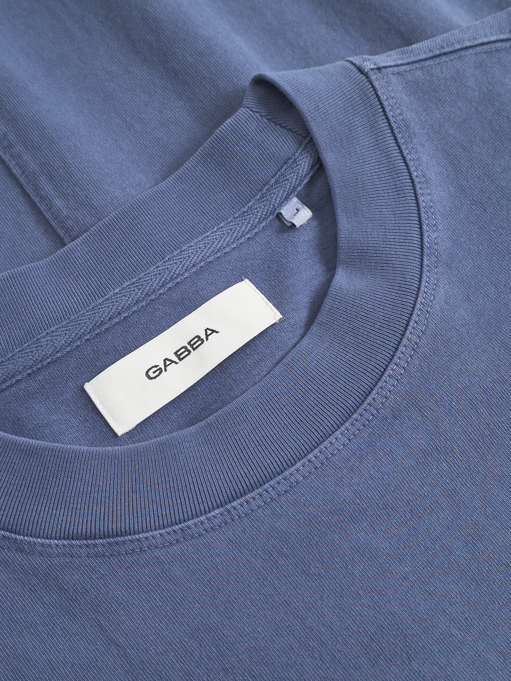 Close-up of the Nigel Wix Boxy Hour SS T-shirt in vintage indigo, showing a white Gabba fabric label sewn inside the crew-neck collar.
