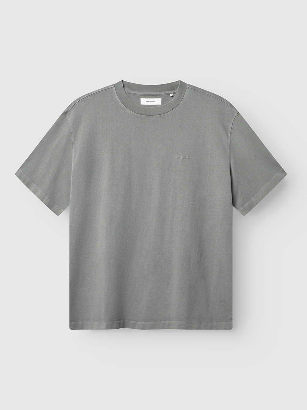 The Gabba Nigel Wix Boxy Hour SS in Dust Sage Green is a short-sleeve, boxy-fit cotton t-shirt with a crew neck, featuring a small logo on the left chest and vintage texture, displayed on a light background.