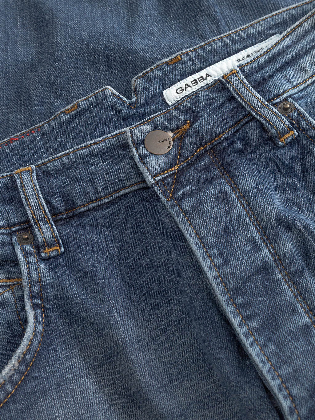 Close-up of Gabba GABalex Cros Cropped jeans in mid blue denim with visible stitching, belt loops, metal button, white Gabba label, classic faded look, and subtle cross hatch fabric details.