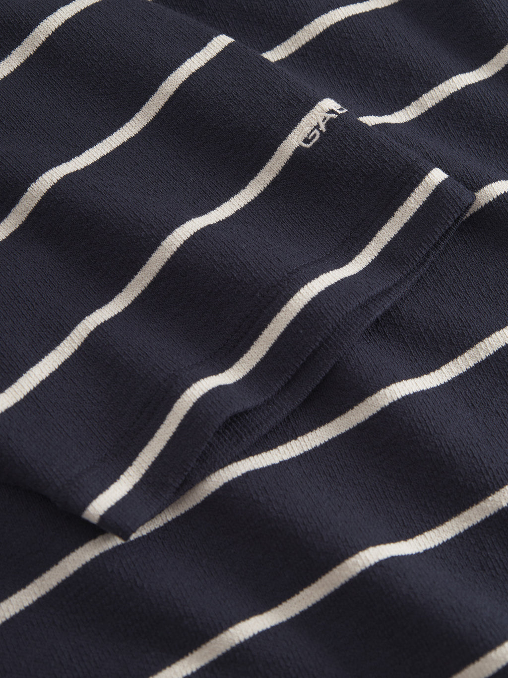 Close-up of the Dune Crepe Stripes SS GOTS t-shirt by Gabba in navy stripe, made from organic cotton, with evenly spaced white stripes and a small embroidered white logo near the top right corner.
